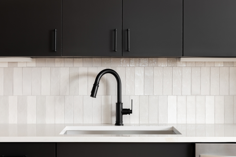 A,kitchen,faucet,detail,with,black,cabinets,,a,vertical,subway